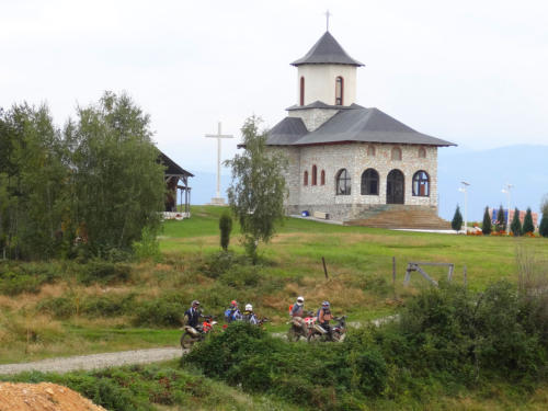 Gruppe von Endurofahrern vor einer traditionellen Kirche in den Karpaten